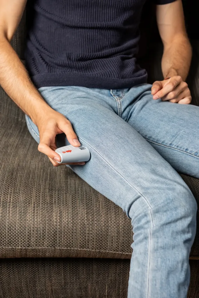 Une personne assise s’injecte ZENEO® dans la cuisse, à travers son jean